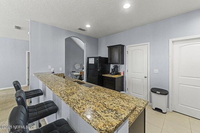 3410 Ridgeview Dr, Green Cove Springs, FL 32043 - kitchen featuring freestanding refrigerator, arched walkways, a sink, a kitchen bar, and light stone countertops