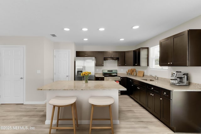 12171 Calais St, Jacksonville, FL 32224 - kitchen with dark brown cabinets, stainless steel appliances, a kitchen bar, under cabinet range hood, and a kitchen island