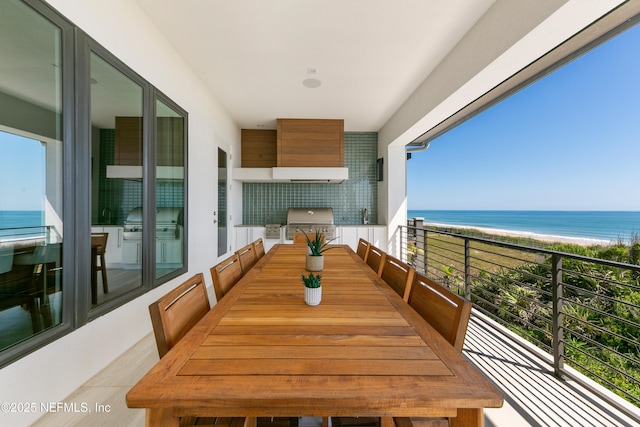 balcony with exterior kitchen, a water view, and area for grilling