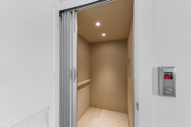 room details with recessed lighting, elevator, and wood finished floors