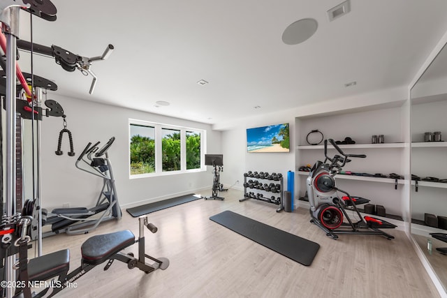 exercise area featuring baseboards, visible vents, and wood finished floors