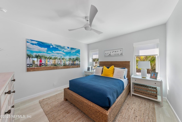 bedroom featuring baseboards, multiple windows, a ceiling fan, and light wood-style flooring