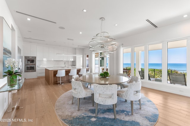 dining space featuring light wood-type flooring, recessed lighting, and a notable chandelier