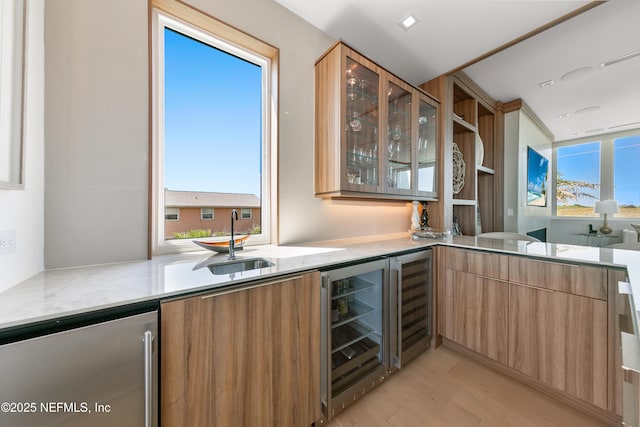 bar featuring a sink, light wood finished floors, wine cooler, and refrigerator