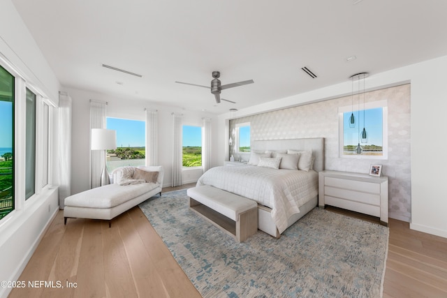 bedroom with baseboards, ceiling fan, wood finished floors, and visible vents