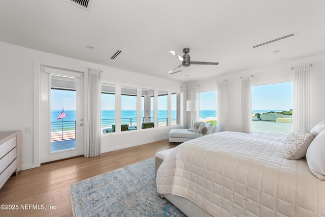 bedroom with baseboards, wood finished floors, multiple windows, and access to exterior