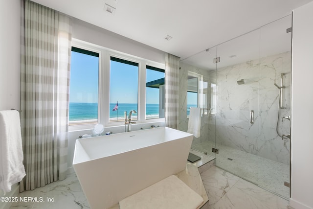 bathroom featuring a water view, marble finish floor, a freestanding tub, and a marble finish shower