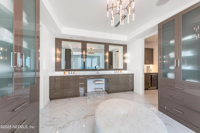 full bath featuring an inviting chandelier, vanity, marble finish floor, wine cooler, and a tray ceiling