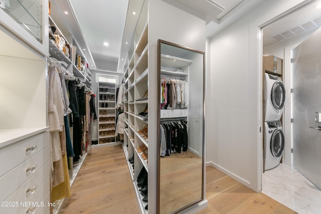 interior space featuring stacked washer / drying machine, light wood-style flooring, and visible vents