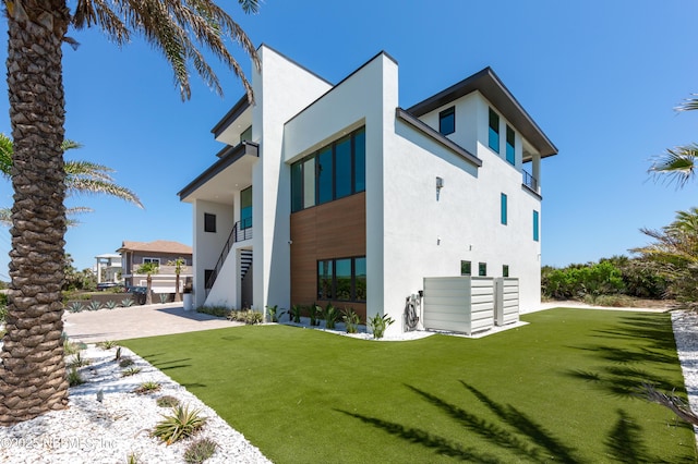 back of house with a lawn, stucco siding, and stairway