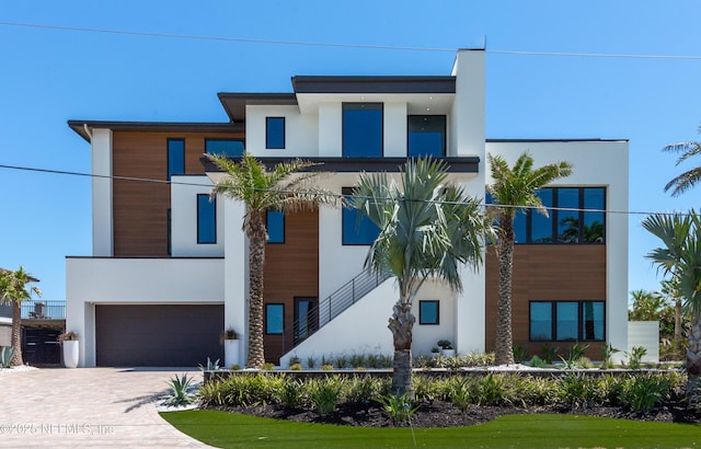 view of front of house with decorative driveway, a garage, and stucco siding