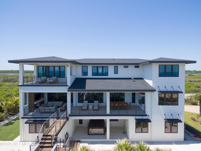 back of house with stairs, stucco siding, a balcony, and an outdoor hangout area