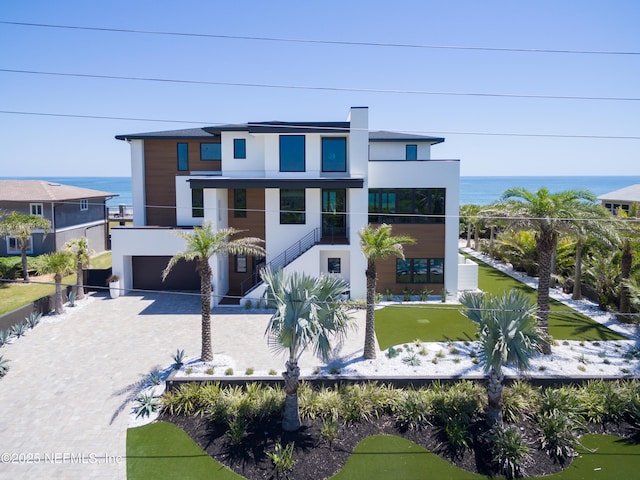 contemporary house with fence private yard, stucco siding, an attached garage, a water view, and driveway