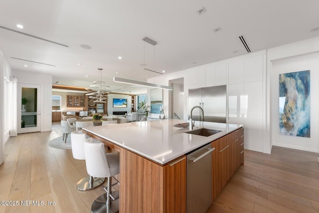 kitchen featuring open floor plan, modern cabinets, a spacious island, a sink, and appliances with stainless steel finishes