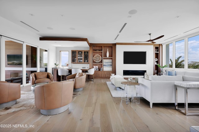 living area featuring ceiling fan, built in features, and light wood finished floors
