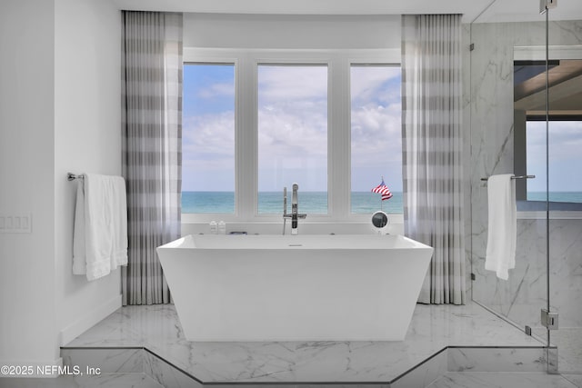 bathroom with a water view, plenty of natural light, a soaking tub, and marble finish floor