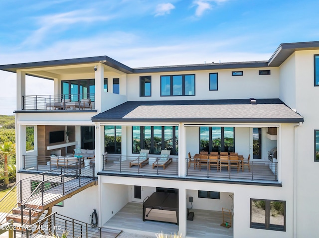 back of house with an outdoor hangout area, a balcony, roof with shingles, and stucco siding