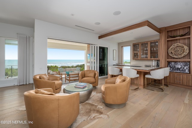 living room featuring visible vents, light wood finished floors, and beamed ceiling