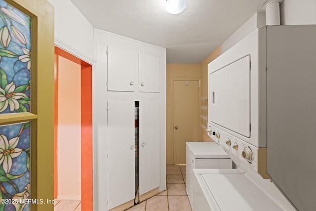 washroom with stacked washer and clothes dryer, laundry area, and light tile patterned floors