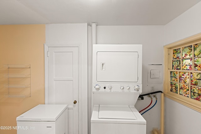 clothes washing area featuring stacked washer and dryer and laundry area