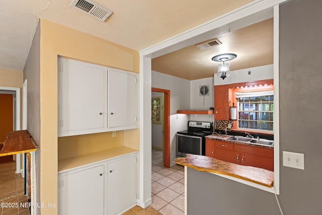 kitchen featuring electric stove, light tile patterned floors, a sink, and visible vents