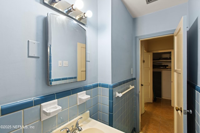 bathroom featuring tile walls, tile patterned floors, a wainscoted wall, and a sink