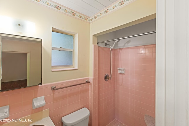 bathroom featuring vanity, tile walls, a wainscoted wall, toilet, and tiled shower