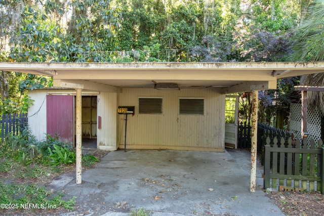 view of outdoor structure with fence and a carport