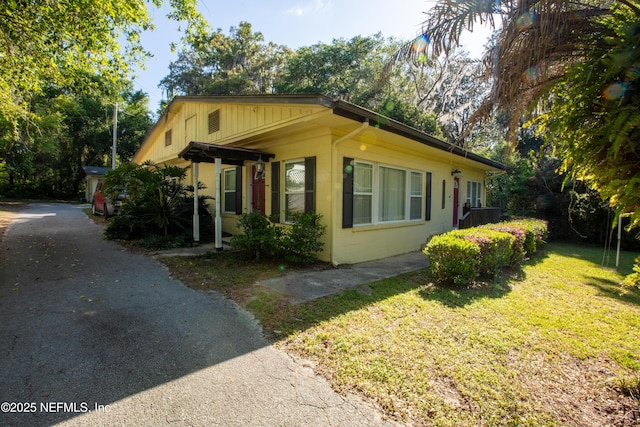 view of property exterior featuring a lawn, driveway, and concrete block siding