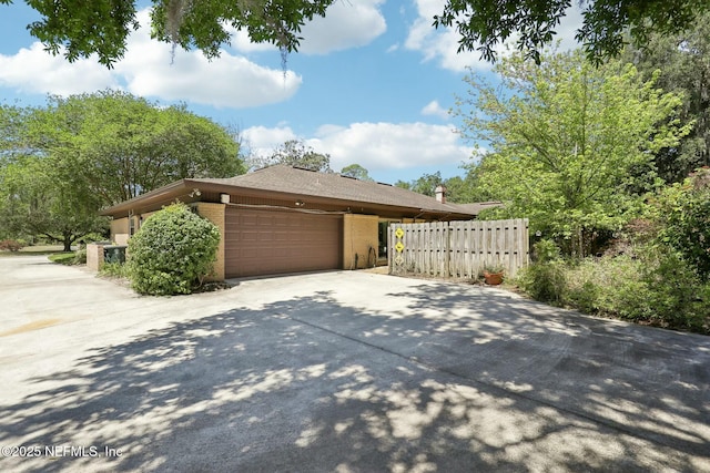 2815 Sylvan Ln S, Jacksonville, FL 32257 - view of side of property with a garage, brick siding, concrete driveway, and fence