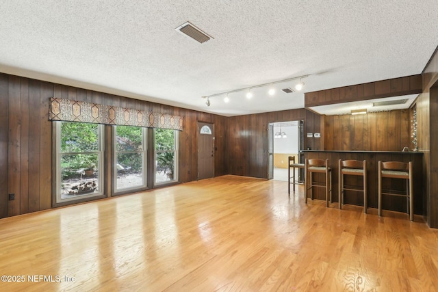 2815 Sylvan Ln S, Jacksonville, FL 32257 - unfurnished living room featuring wood walls, light wood finished floors, a textured ceiling, and visible vents
