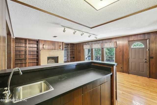 2815 Sylvan Ln S, Jacksonville, FL 32257 - kitchen featuring a sink, a textured ceiling, dark countertops, light wood-style floors, and a fireplace