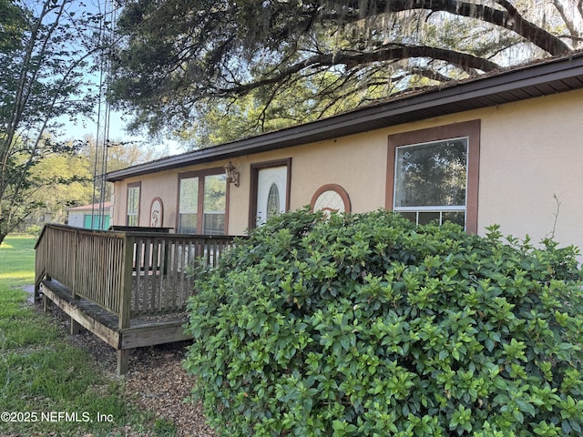 view of exterior entry with a deck and stucco siding