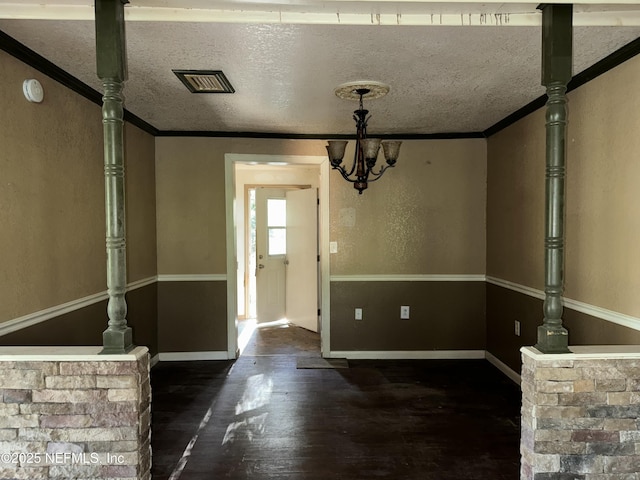 unfurnished dining area with crown molding, visible vents, a chandelier, and wood finished floors