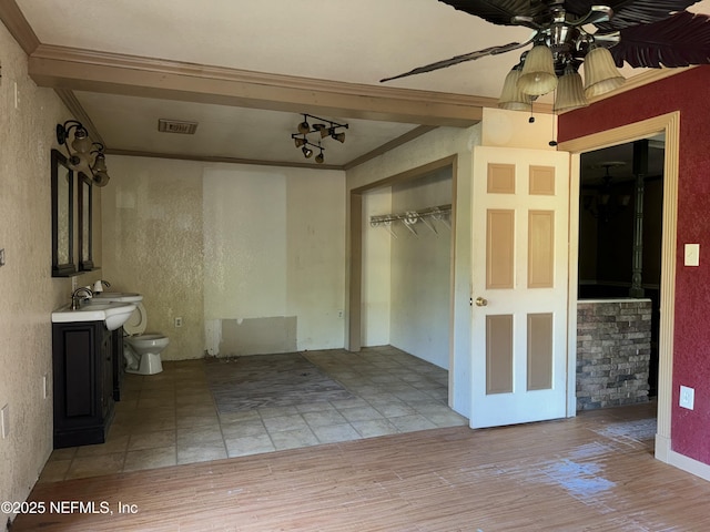 interior space featuring vanity, a textured wall, toilet, visible vents, and ceiling fan