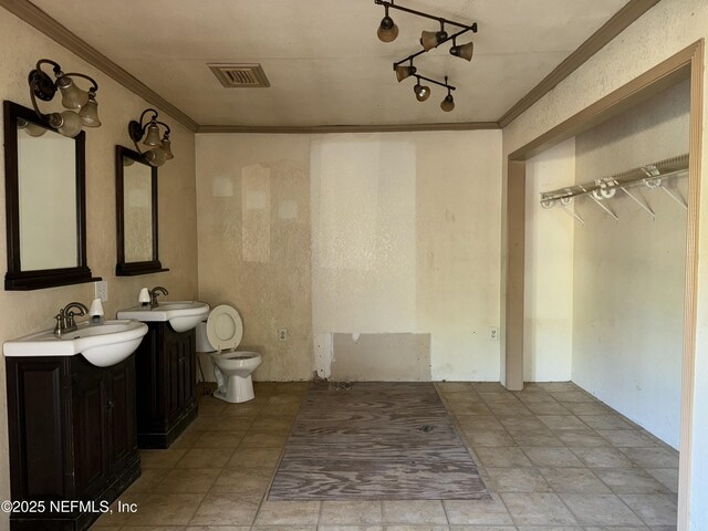 bathroom featuring toilet, crown molding, a sink, and visible vents