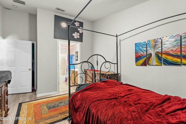 3671 Kirkpatrick Cir Unit 14, Jacksonville, FL 32210 - bedroom with ensuite bathroom, visible vents, a textured ceiling, and wood finished floors