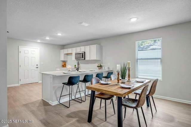 5454 Amazon Ave, Jacksonville, FL 32254 - dining area with light wood-style floors, a textured ceiling, and baseboards