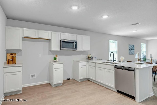 5454 Amazon Ave, Jacksonville, FL 32254 - kitchen featuring white cabinets, stainless steel appliances, visible vents, a sink, and a peninsula