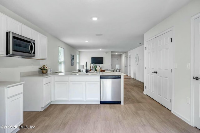 5454 Amazon Ave, Jacksonville, FL 32254 - kitchen with light wood finished floors, stainless steel appliances, a sink, a peninsula, and open floor plan