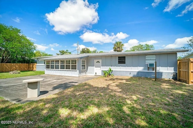 view of front of house with fence, a front lawn, board and batten siding, cooling unit, and a patio