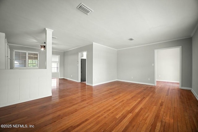 unfurnished living room featuring baseboards, ornamental molding, wood finished floors, and visible vents