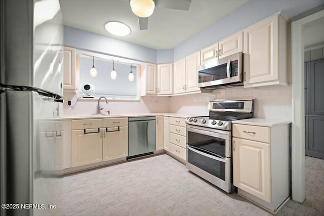 kitchen featuring a sink, light countertops, tasteful backsplash, a ceiling fan, and appliances with stainless steel finishes