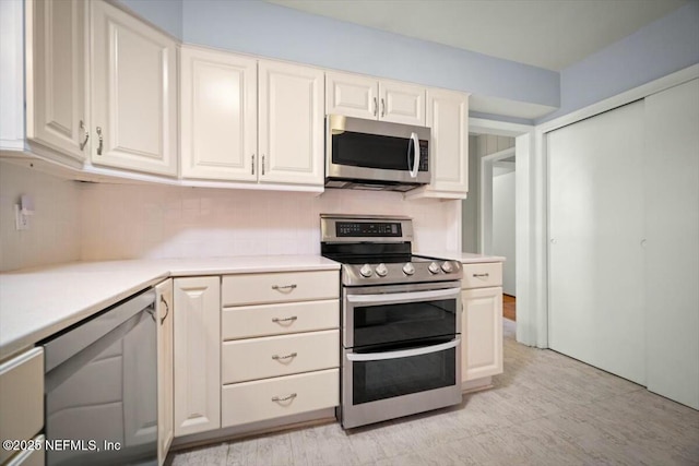 kitchen featuring backsplash, stainless steel appliances, white cabinetry, and light countertops