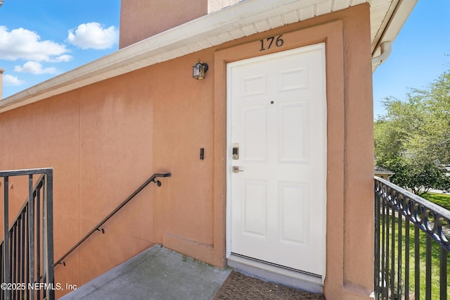 entrance to property featuring stucco siding and a balcony