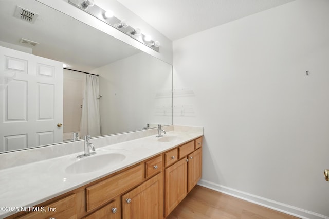 bathroom with wood finished floors, visible vents, and a sink