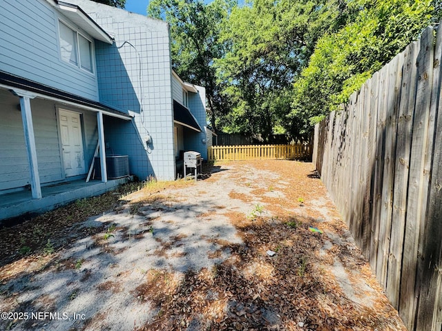view of yard featuring a porch, a fenced backyard, and central AC unit