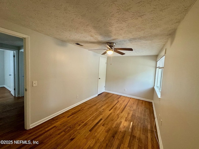 spare room with wood finished floors, visible vents, baseboards, a textured ceiling, and ceiling fan