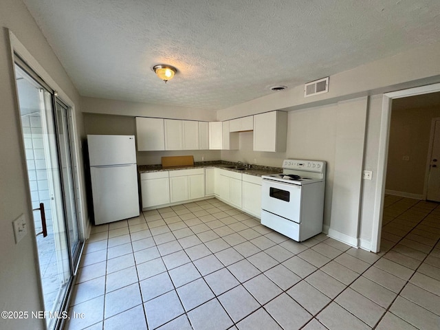 kitchen with dark countertops, visible vents, light tile patterned floors, white appliances, and a textured ceiling