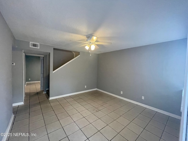 empty room with baseboards, a ceiling fan, visible vents, and light tile patterned floors